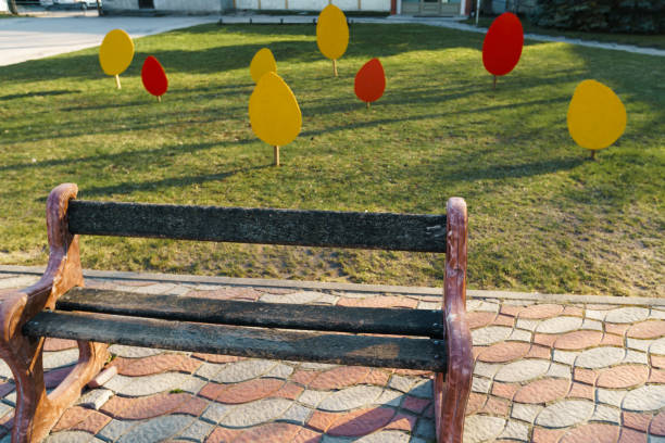 istock Small city bench standing on a pavement near a tree 1144227760