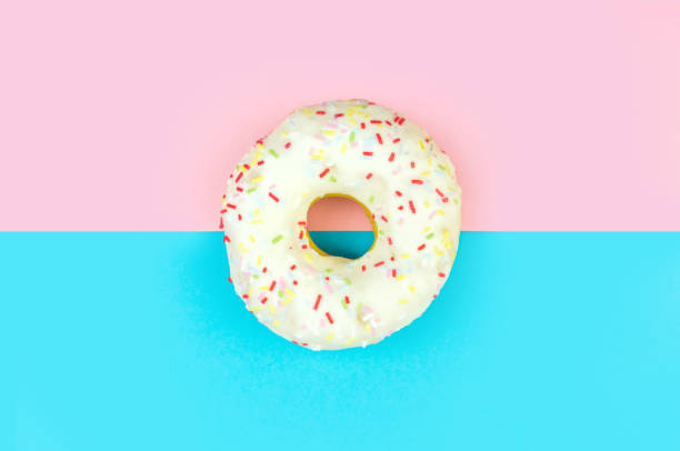 istock White round doughnut on pink and blue background 1144230289