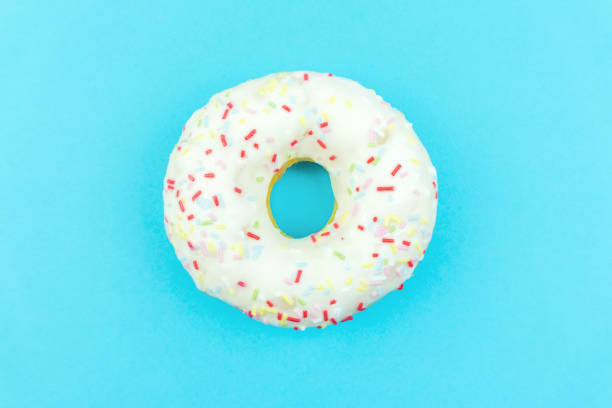 istock White round doughnut on blue background. Flat lay, top view. 1144230293