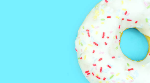 istock Full frame of white doughnut with sprinkles on blue background. Flat lay, top view. 1144230298