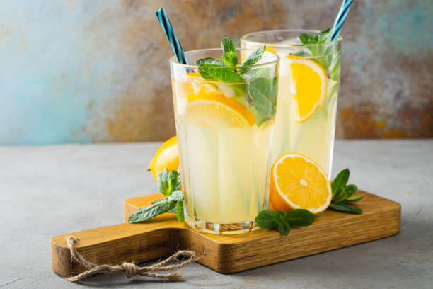 istock Two glass with lemonade or mojito cocktail with lemon and mint, cold refreshing drink or beverage with ice on rustic blue background. Copy space 1144231070