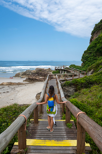 A young woman walks on a boardwalk that leads to Gruta das Encantadas, a grotto on Ilha do Mel in Brazil's Paraná state. (April 3, 2019)