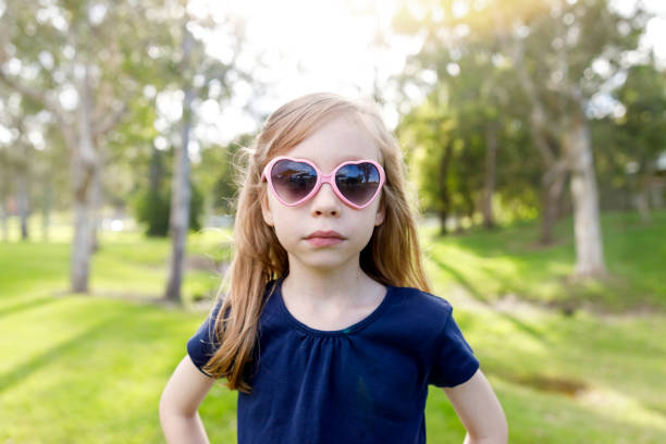 Kid With Cool Attitude Wearing Sunglasses In The Park with soft backlighting