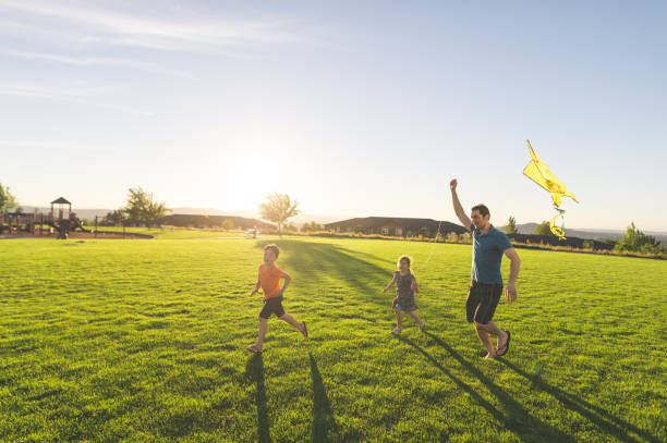 papa flying kites met zijn kinderen op het park - park stockfoto's en -beelden