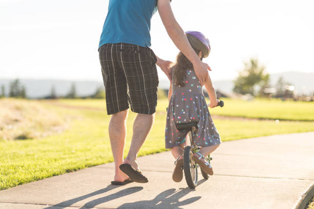 istock Dad helping his daughter learn to ride a bike 1144238754