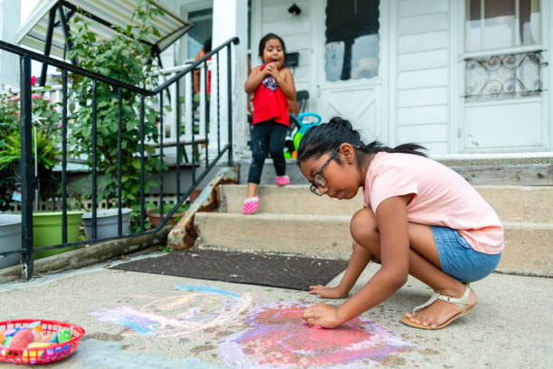 Two little Latino Mexican-American girls, sisters, drawing with chalk at the porch of his house in Pennsylvania Two little Latino Mexican-American girls, sisters, drawing with chalk at the porch of his house in Pennsylvania, USA at the sunny summer day hot mexican girls stock pictures, royalty-free photos & images