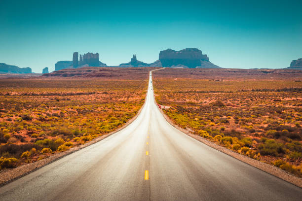 Classic panorama view of historic U.S. Route 163 running through famous Monument Valley on a beautiful sunny day in summer, Utah, USA