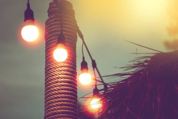 blurred light on sunset with yellow string lights decor in beach restaurant