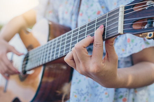Close up, Young woman musician playing acoustic guitar at outdoors