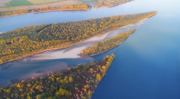 Aerial View over Danube River at Sunset in Autumn. Drone Point of View over the frontier between two countries with Reflections in the Water and Majestic Sunset danube valley stock pictures, royalty-free photos & images