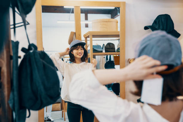 洋服店で帽子を取ろうとする若い女性 - hat shop ストックフォトと画像