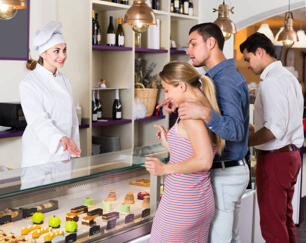 istock Cheerful chef woman is offering cakes from showcase 1144275962