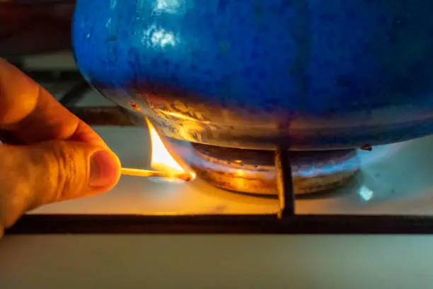 A man lighting the gas-stove with a match