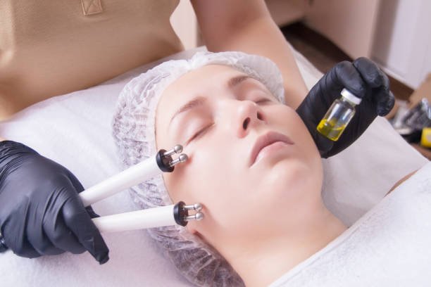 the cosmetologist makes the apparatus procedure of microcurrent therapy of a beautiful, young woman in a beauty salon. - ionization imagens e fotografias de stock