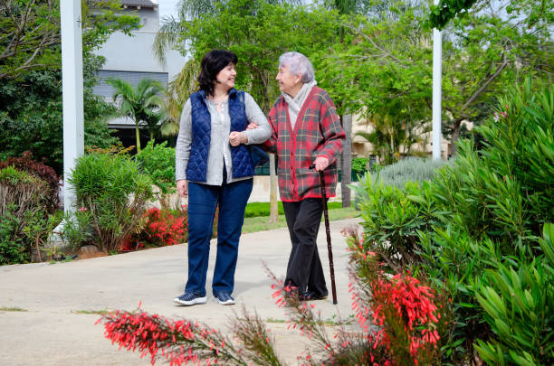 Modern psychotherapist walking with an elderly patient in a city park stock photo