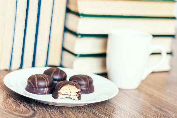 Stack of books, cup of coffee and chocolate cookies white plate