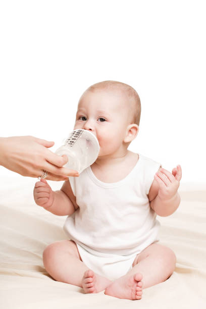 istock Baby drinking milk from a bottle lying on a white bed at home 1144284836
