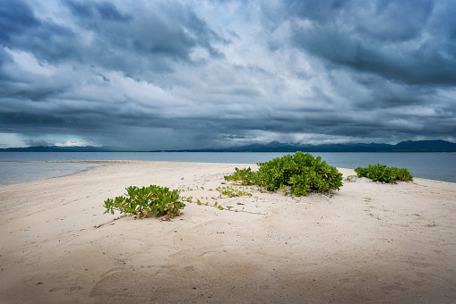 White sand beach of a small island as storm clouds approach in the Pacific Ocean