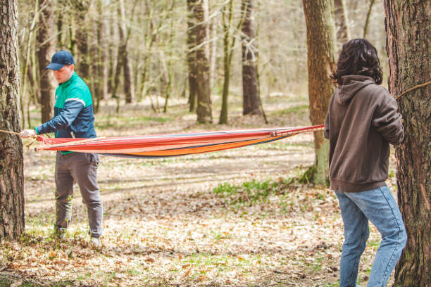 woman with man tie up hammock in forest woman with man tie up hammock in forest between trees women lying down grass wood stock pictures, royalty-free photos & images