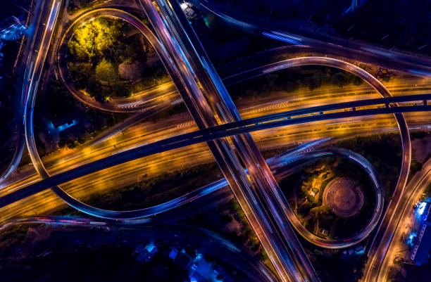 échangeur routier dans la ville la nuit avec le mouvement de lumière de voiture de véhicule, vue aérienne. - traffic roundabout photos et images de collection