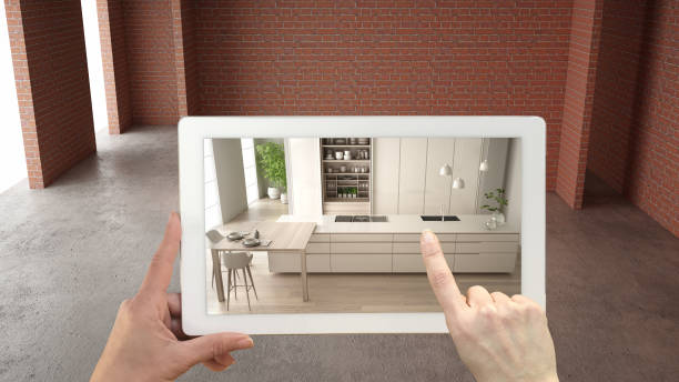 istock Augmented reality concept. Hand holding tablet with AR application used to simulate furniture and design products in interior construction site, modern kitchen with island, top view 1144286404