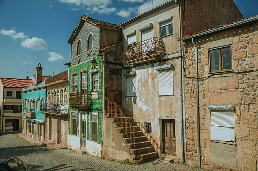 Old houses with worn facade and staircase with rusty railing on deserted alley, in a sunny day at Belmonte. A cute small town, birthplace of the navigator Pedro Alvares Cabral, on eastern Portugal.