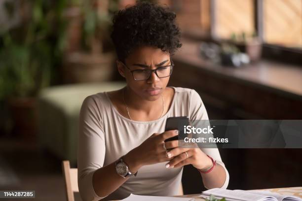 Upset Confused African Woman Holding Cellphone Having Problem With Phone Stock Photo - Download Image Now
