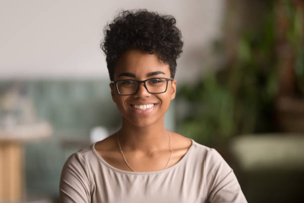 Headshot portrait of happy mixed race african girl wearing glasses Head shot portrait of happy mixed race girl wearing glasses, smiling african american millennial woman posing indoor, pretty positive female student businesswoman young professional looking at camera human face photos stock pictures, royalty-free photos & images