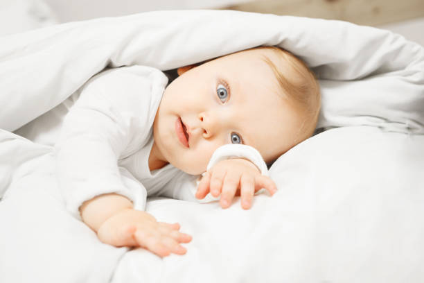 istock Baby lies in comfortable bed under warm blanket 1144287842