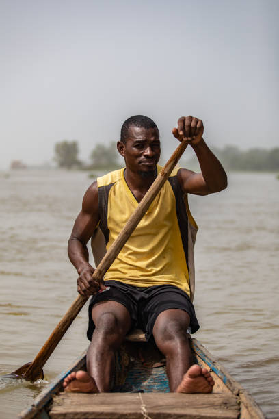 Young muscular African man driving a canoe on Niger river close to Niamey stock photo