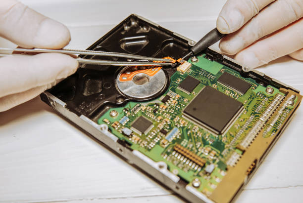 istock Man repairing hard disk. Inside details of the old personal computer. Broken PC.  Screwdriver and pincers in hands. 1144289788