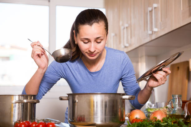 istock Young woman cooks soup in the kitchen 1144291195
