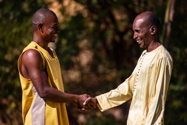 Two African men shaking hands in a field on the banks of Niger river close to Niamey stock photo