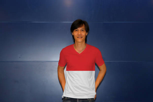 istock Man wearing Indonesia flag pattern shirt standing on the blue wall background. 1144296473