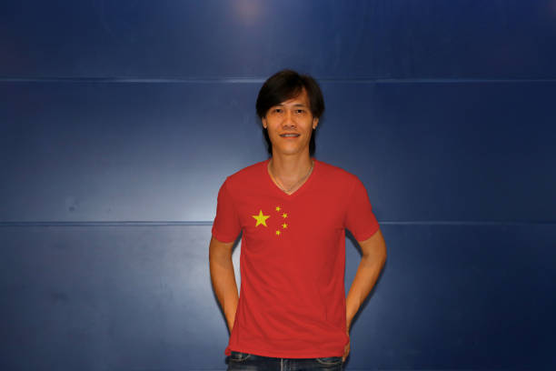 istock Man wearing China flag pattern shirt standing on the blue wall background. 1144296556