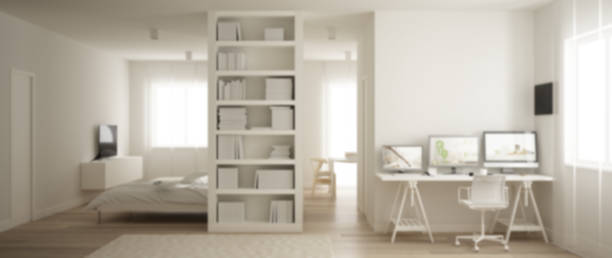 istock Blur background interior design, one room apartment with parquet floor, home workplace with desk in white living room, bookshelf, Murphy bed, modern architecture concept 1144298348
