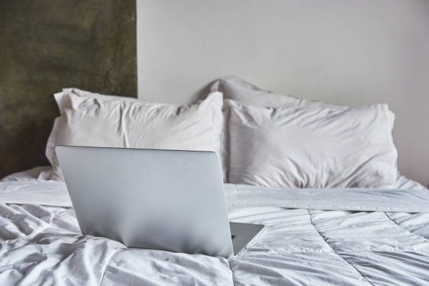 istock Laptop on white bed work at home concept 1144302459