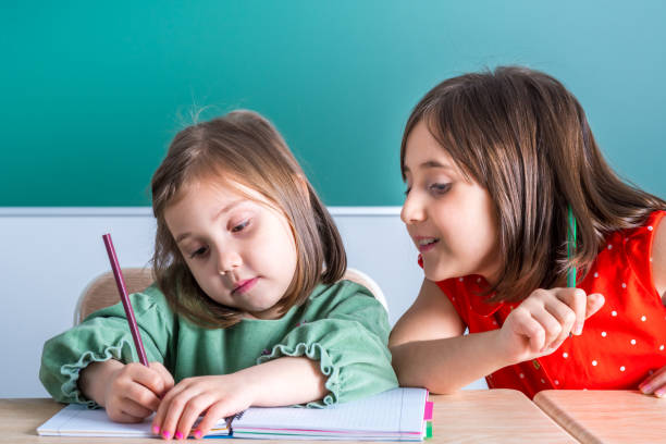 istock older sister looks at her younger sister as she draws in a notebook 1144304138