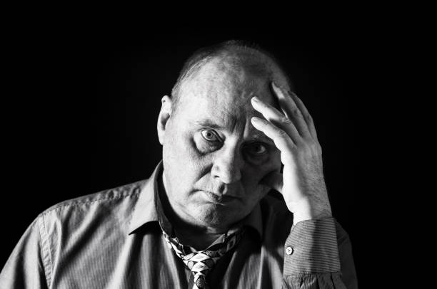 monochrome portrait of pensive office clerk against black background - portrait black and white senior men wisdom imagens e fotografias de stock