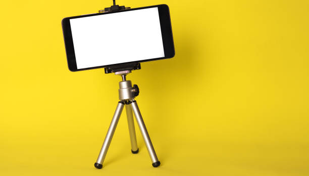 istock Blank phone on a tripod on a bright yellow background with copyspace. Mobile blog 1144307676