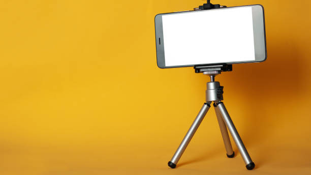 istock Blank phone on a tripod on a bright yellow background with copyspace. Mobile blog 1144307688