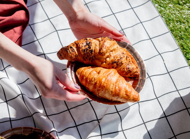istock Female holding a plate with croissants over checked cloth 1144311776
