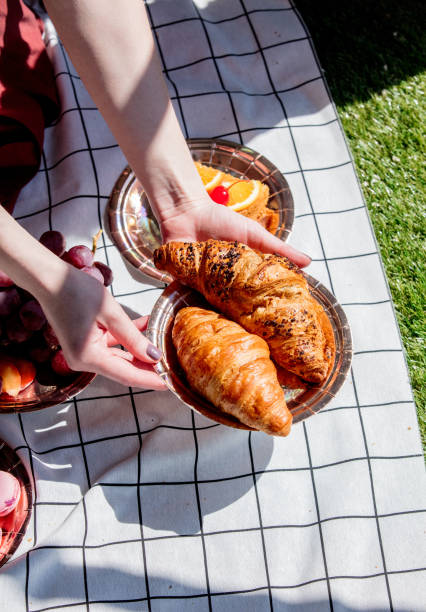 istock Female holding a plate with croissants over checked cloth 1144311785