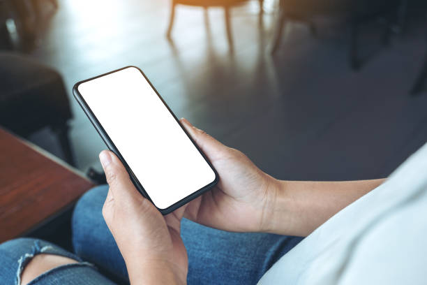 istock Mockup image of woman's hands holding black mobile phone with blank white screen in cafe 1144312274