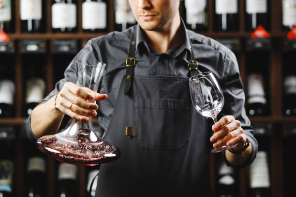 barmann in schürze hält gefäß mit rotwein und glas - decanter wine wineglass red wine stock-fotos und bilder