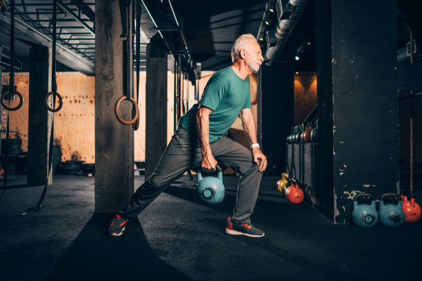 istock Active elderly male doing a one arm kettlebell exercise in a gym gym 1144317013