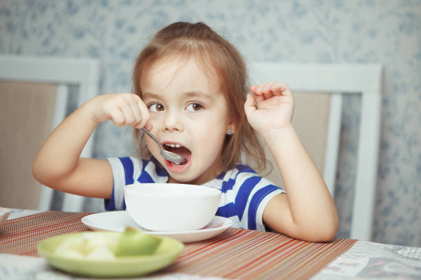 istock Child holding spoon in her hand eating dish 1144318759