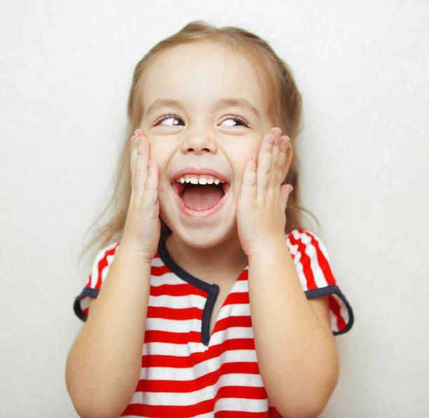 istock Embarrassed little girl with broad smile thouches her cheeks 1144319102