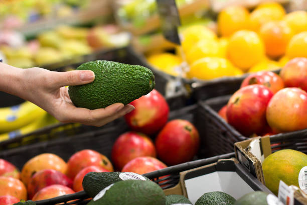 frauen wählen avocado im supermarkt - refrigerator healthy eating mango fruit stock-fotos und bilder