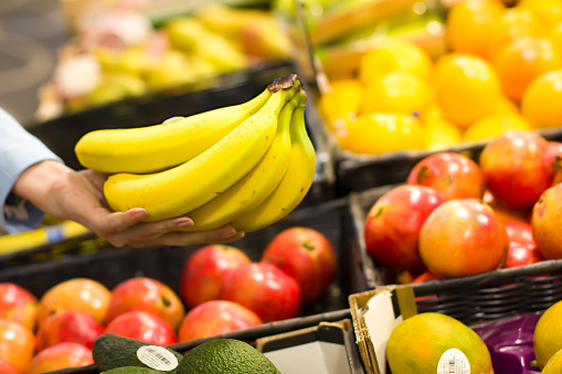 Women hand choosing bananas at supermarket